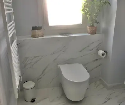 a white bathroom with a toilet and a window at Angel Suites in Nicosia