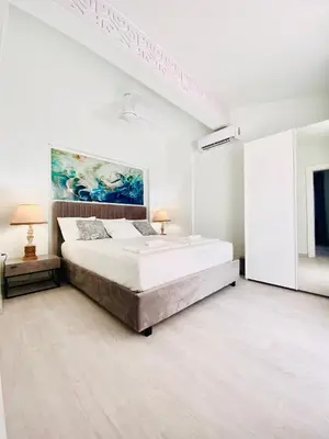 a white bedroom with a bed and a painting on the wall at SANDY BAY Villa in Ayia Napa