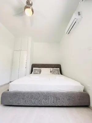 a bed in a white room with a ceiling fan at SANDY BAY Villa in Ayia Napa
