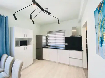 a kitchen with white cabinets and a black refrigerator at SANDY BAY Villa in Ayia Napa