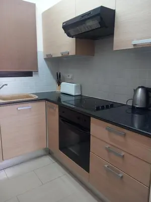 a kitchen with wooden cabinets and a black counter top at BarLee's Apartment in Paralimni