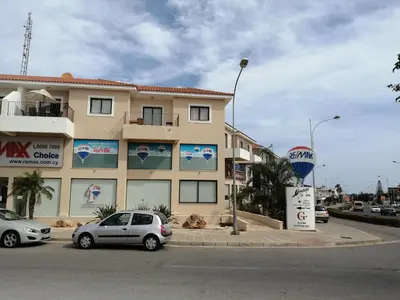 a building with two cars parked in a parking lot at BarLee's Apartment in Paralimni