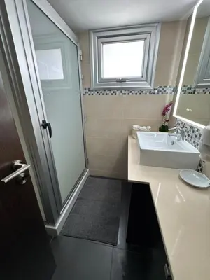 a bathroom with a sink and a shower with a window at Topikos Apartments in Ayia Napa