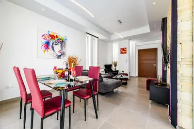 a living room with a dining room table and red chairs at Mylos Lifestyle Seaview Villa #21 in Protaras