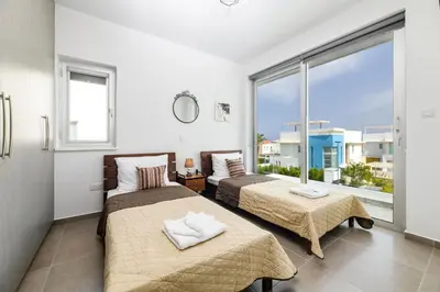 two beds in a room with a large window at Mylos Lifestyle Seaview Villa #21 in Protaras