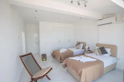 a white room with two beds and a chair at Apt Misia Enas - Modern 2 Bedroom Apartment With Sea Views - Close To Ayia Napa in Ayia Napa
