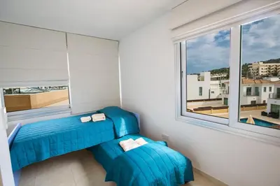 a room with two blue chairs and a window at Apt Lasonos Asimi - Luxury 3 Bedroom Protaras Apartment - Communal Pool in Protaras