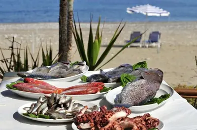 a table with four plates of seafood on the beach at Apt Lasonos Asimi - Luxury 3 Bedroom Protaras Apartment - Communal Pool in Protaras