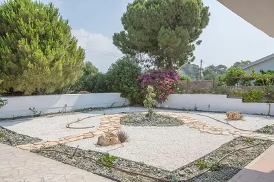a garden with a tree and two cats laying on the ground at Villa Nepou - Beautiful 4 Bedroom Villa - Located In Ayia Napa in Ayia Napa