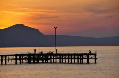 a pier with people fishing on the water at sunset at Villa Petreris Dyo - Lovely 3 Bedroom Central Ayia Napa Villa With Pool in Ayia Napa