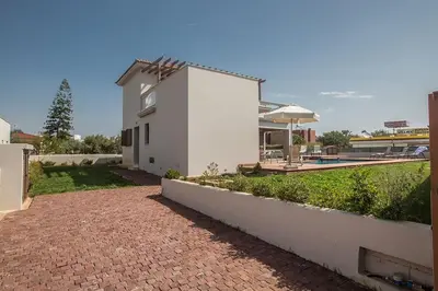 a white house with a brick walkway next to a pool at Villa Petreris Dyo - Lovely 3 Bedroom Central Ayia Napa Villa With Pool in Ayia Napa