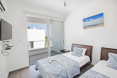 a white room with two beds and a tv at Villa Ochosto Eos - Luxury 5 Bedroom Protaras Villa With Private Pool - Close in Protaras