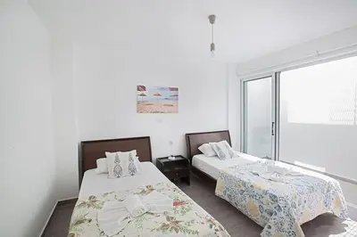 two beds in a room with a window at Villa Ochosto Eos - Luxury 5 Bedroom Protaras Villa With Private Pool - Close in Protaras