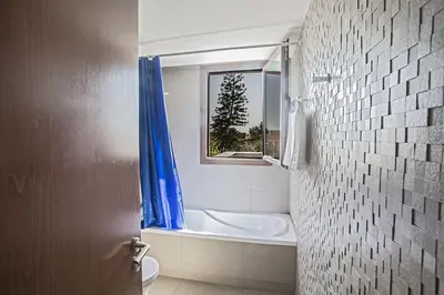 a bathroom with a tub and a toilet and a window at Villa Petreris Enas - Stunning 3 Bedroom Central Ayia Napa Villa With Pool in Ayia Napa