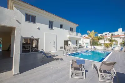 a patio with chairs and a swimming pool next to a building at Villa Dafnis Platina - Lovely 4 Bedroom Protaras Villa With Private Pool in Protaras