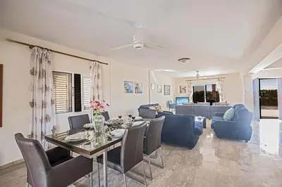 a living room with a table and chairs and a couch at Villa Magusta - Modern 4 Bedroom Ayia Thekla Villa With Pool in Ayia Napa
