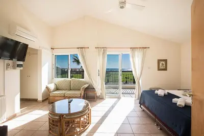 a bedroom with a bed and a couch and a tv at Villa Magusta - Modern 4 Bedroom Ayia Thekla Villa With Pool in Ayia Napa