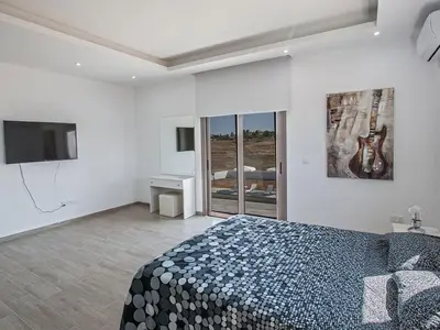 a white bedroom with a bed and a television at Villa Ioanni Chrysos - Luxury And New 6 Bedroom Protaras Villa in Protaras