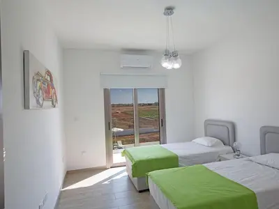 a room with two beds with green sheets and a window at Villa Ioanni Chrysos - Luxury And New 6 Bedroom Protaras Villa in Protaras