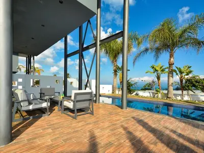 a patio with chairs and a pool with palm trees at Villa Limni Dyo - Luxurious Contemporary 3 Bedroom Villa With Sea Views And Hot in Paralimni