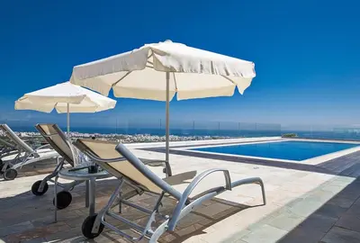 a table and chairs with an umbrella and a pool at Villa Saranta Gold - Exquisite 3 Bedroom Protaras Villa With Private Pool in Protaras