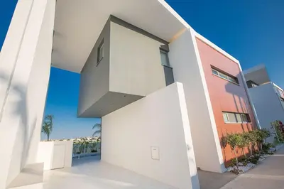 a white house with a red building at Villa Limni Enas - Luxury And Contemporary 3 Bedroom Kapparis Villa With Sea View in Paralimni