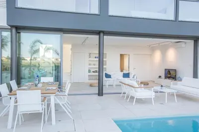 a living room with a table and chairs and a pool at Villa Limni Enas - Luxury And Contemporary 3 Bedroom Kapparis Villa With Sea View in Paralimni