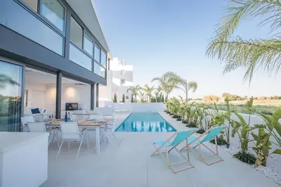 a patio with a table and chairs and a swimming pool at Villa Limni Enas - Luxury And Contemporary 3 Bedroom Kapparis Villa With Sea View in Paralimni
