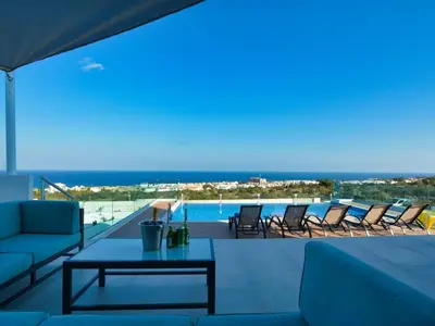 a patio with chairs and a table and a pool at Villa Kono Provoles - Luxury 4 Bedroom Protaras Villa With Stunning Panoramic in Protaras