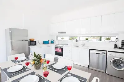 a white kitchen with a table with glasses of wine at Villa Ochosto Loux - Fabulous 5 Bedroom Protaras Villa With Private Pool in Protaras