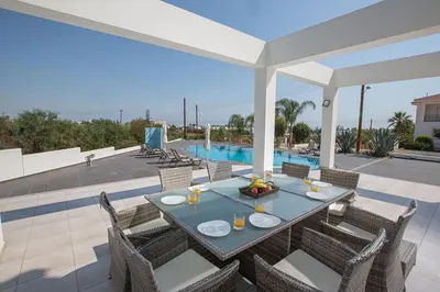 a patio with a table and chairs and a pool at Villa Protara Chrysos - Beautiful 5 Bedroom Protaras Villa - Walking Distance in Protaras