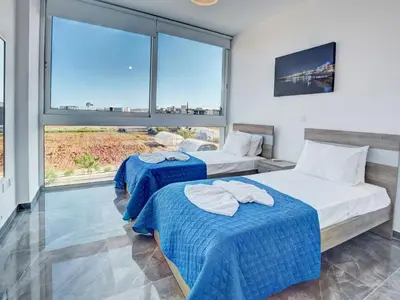 two beds in a room with large windows at Villa Manta Chrysos - Brand New Luxury 3 Bedroom Protaras Villa in Protaras