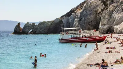 a boat on a beach with people in the water at Villa Kono Sunshine - Luxury 4 Bedroom Cape Greco - Villa Close To Beach in Protaras