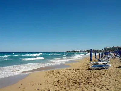 a beach with several umbrellas and the ocean at Villa Dafnis Helios - Lovely 3 Bedroom Central Protaras Villa With Pool in Protaras