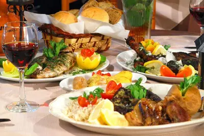 a table with plates of food and a glass of wine at Villa Dafnis Helios - Lovely 3 Bedroom Central Protaras Villa With Pool in Protaras
