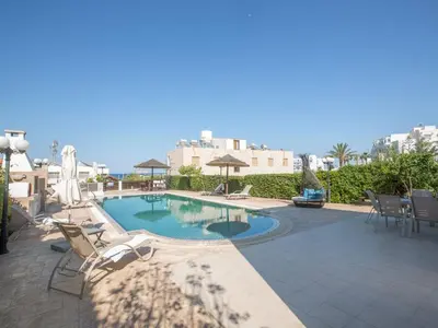 a swimming pool with chairs and tables and buildings at Villa Lefko Sunshine - Lovely 4 Bedroom Protaras Villa With Pool in Protaras