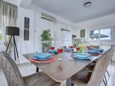 a dining room with a wooden table with wine glasses at Villa Oforo Selene - Stunning 4 Bedroom Villa - By Fig Tree Bay Beach - Sea View in Protaras