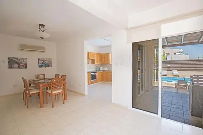 a kitchen and dining room with a table and chairs at Villa Protaras Eos, Modern 3Bdr Protaras Villa With Pool, Short Walk in Protaras