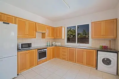 a kitchen with wooden cabinets and a white refrigerator at Villa Protaras Eos, Modern 3Bdr Protaras Villa With Pool, Short Walk in Protaras