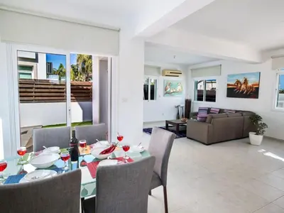 a dining room and living room with a table and chairs at Villa Mesogi, Modern 3Bdr Protaras Villa, Close To Fig Tree Bay Beach in Protaras