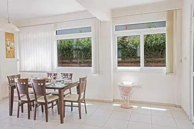 a dining room with a table and chairs and windows at Villa Dafnis Chrysos - Modern 3 Bedroom Protaras Villa With Pool in Protaras