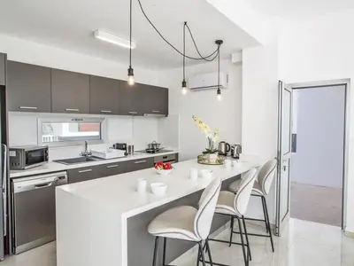 a kitchen with a white counter and stools at Villa Olive Sun, Beautiful, Contemporary 3Bdr Villa With Private Pool in Protaras