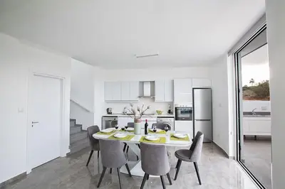 a white kitchen with a dining room table and chairs at Villa Olive Gold, Luxury And Brand New 2Bdr Protaras Villa With Private Pool in Protaras