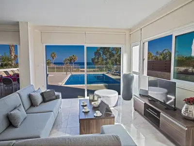a living room with a couch and a tv at Villa Mesogi Seafront, Stunning 4Bdr Fontline Protaras in Protaras