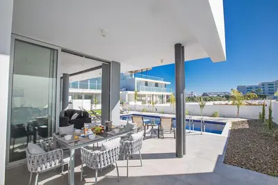 a patio with a table and chairs on a house at Villa Olive Loux,Brand New, Exquisite 5Bdr Protaras Villa With Pool in Protaras