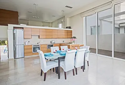 a dining room with a table and white chairs at Villa Fig Tree Bay Frontline,Luxury 4Bdr Sea-Front Protaras Villa With Pool in Protaras