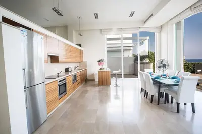a kitchen and dining room with a table and chairs at Villa Fig Tree Bay Frontline,Luxury 4Bdr Sea-Front Protaras Villa With Pool in Protaras
