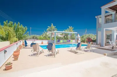 a patio with chairs and a swimming pool at Villa Akefalo - Beautiful 3 Bedroom Protaras Villa With Private Pool in Protaras