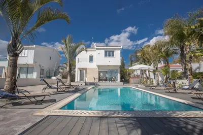 a swimming pool in front of a house with palm trees at Villa Adaman - Stunning 3 Bedroom Seafront Villa With Pool - Close To The Beach in Ayia Napa