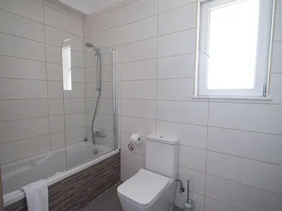 a white bathroom with a toilet and a bath tub at Villa Protaras Miramar, Luxury And New 5Bdr Protaras Villa With Pool in Protaras